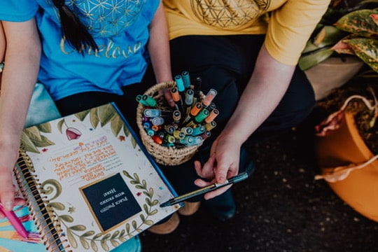 A basket of markers beside an open journal